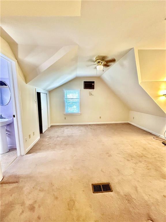 bonus room with lofted ceiling, carpet floors, visible vents, a ceiling fan, and baseboards