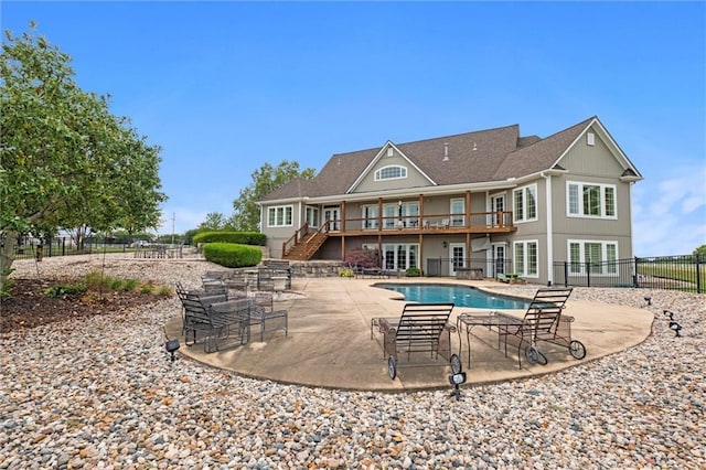 rear view of property with a fenced in pool and a patio area