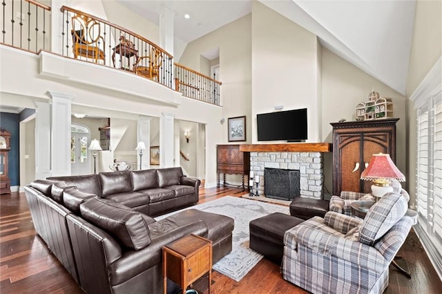 living room with a stone fireplace, high vaulted ceiling, ornate columns, and dark hardwood / wood-style floors