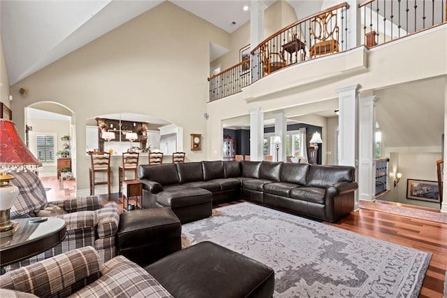 living room featuring hardwood / wood-style floors, high vaulted ceiling, and decorative columns