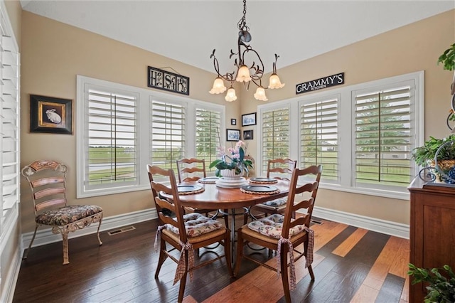 dining area featuring a wealth of natural light, dark hardwood / wood-style floors, and an inviting chandelier