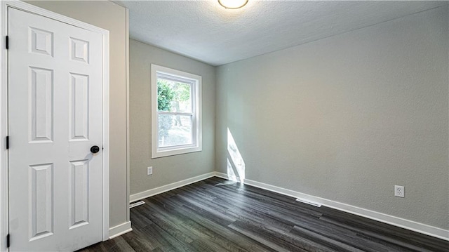 empty room featuring dark wood-type flooring and a textured ceiling