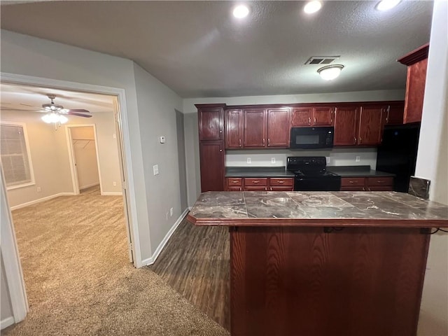 kitchen featuring black appliances, ceiling fan, a breakfast bar, dark colored carpet, and kitchen peninsula