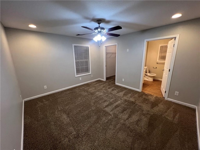 unfurnished bedroom with carpet flooring, ensuite bathroom, ceiling fan, a spacious closet, and a closet