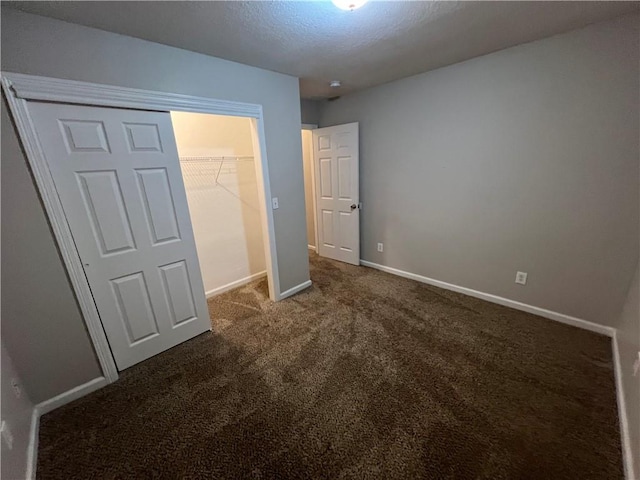 unfurnished bedroom with a closet, dark colored carpet, and a textured ceiling