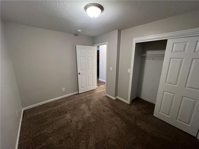 unfurnished bedroom featuring a closet, dark carpet, and a textured ceiling