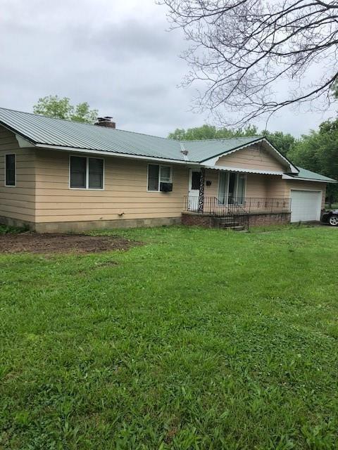 rear view of house with a yard and a garage