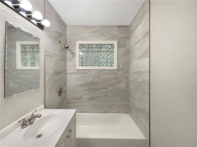 bathroom featuring tiled shower / bath combo, vanity, and a textured ceiling