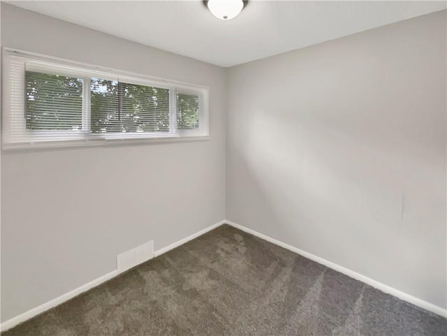 spare room featuring dark colored carpet