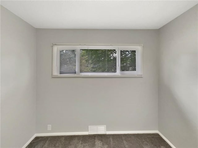 unfurnished room with dark colored carpet