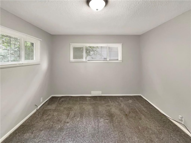 unfurnished room featuring dark carpet and a textured ceiling