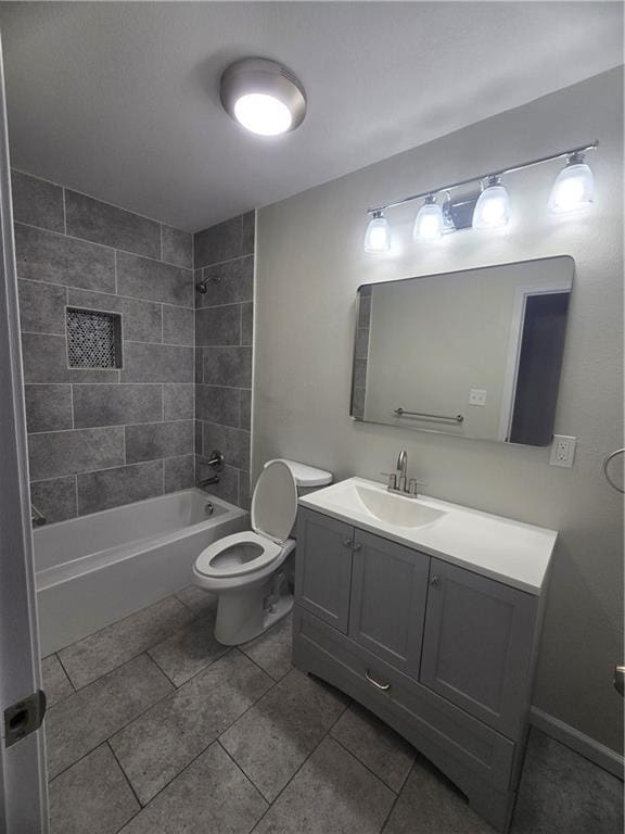 full bathroom featuring tile patterned flooring, tiled shower / bath, vanity, and toilet