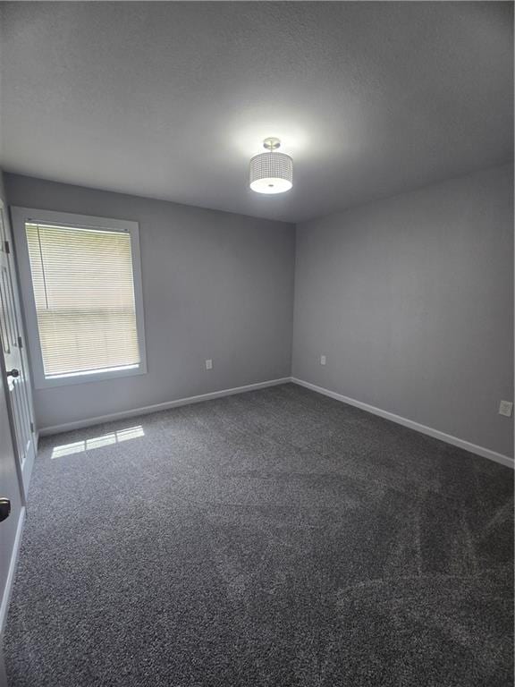 unfurnished room with dark colored carpet and a textured ceiling