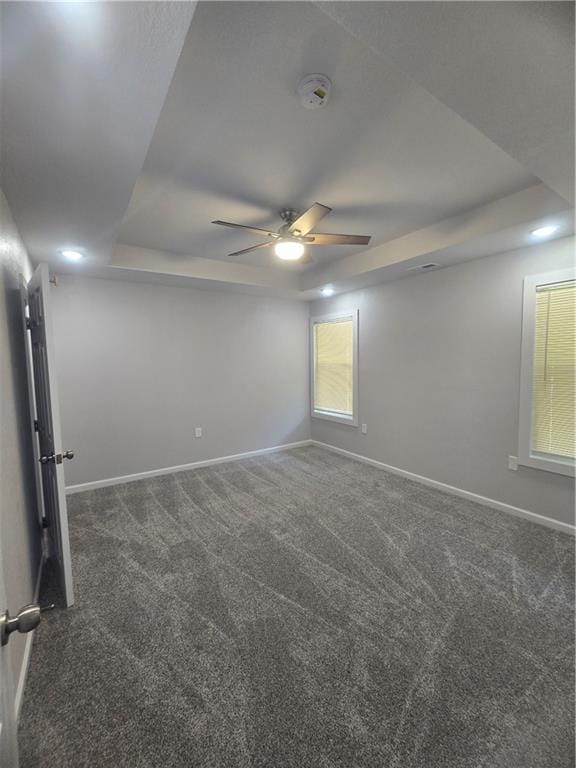 carpeted empty room featuring a raised ceiling and ceiling fan