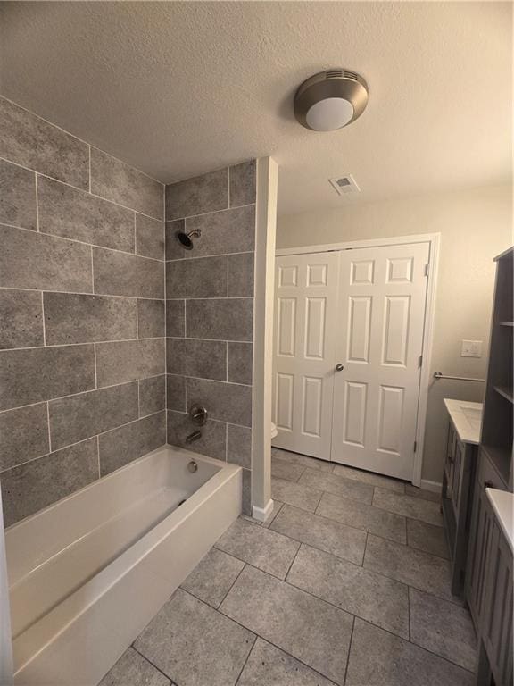 bathroom featuring vanity, tiled shower / bath combo, and a textured ceiling