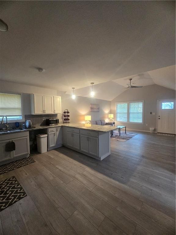 kitchen featuring vaulted ceiling, white cabinetry, sink, dark hardwood / wood-style flooring, and kitchen peninsula