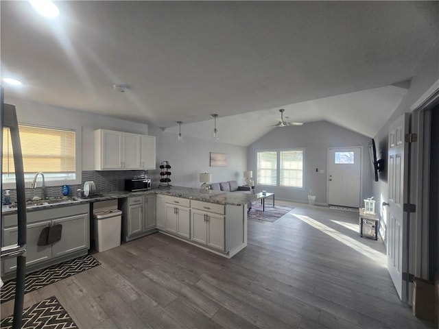 kitchen with vaulted ceiling, kitchen peninsula, hardwood / wood-style flooring, decorative backsplash, and white cabinets