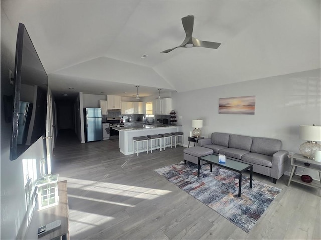 living room with lofted ceiling, ceiling fan, and light hardwood / wood-style flooring