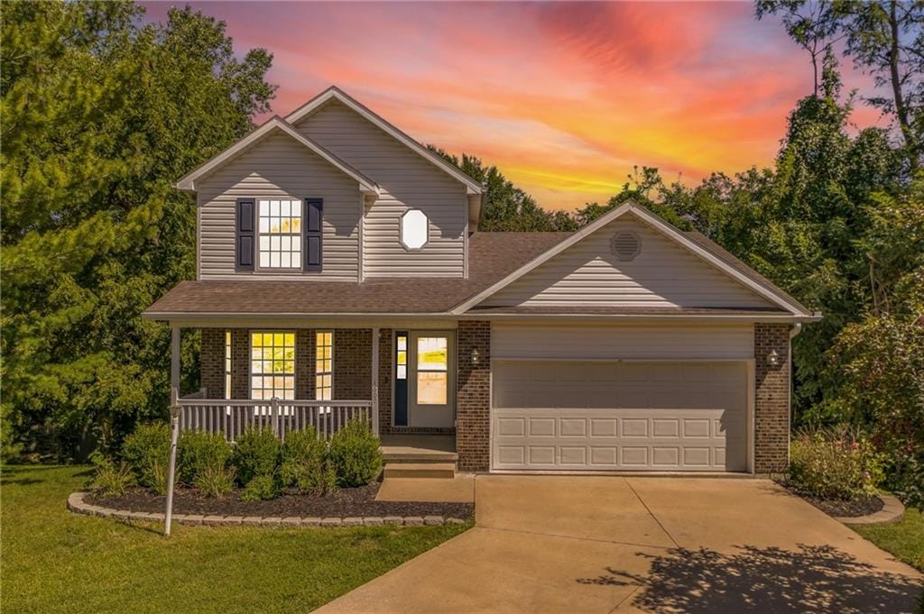 view of front of home featuring a garage, a yard, and covered porch