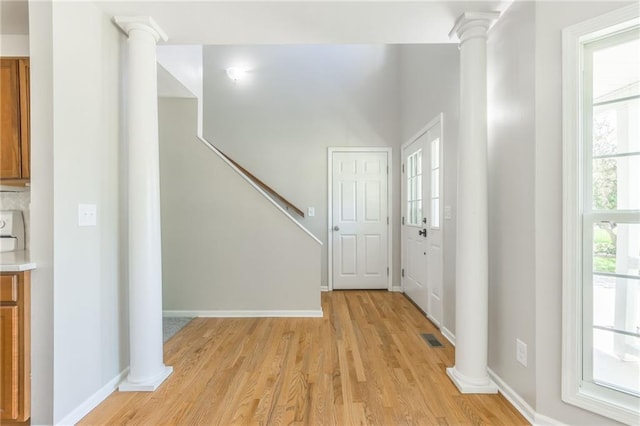 foyer entrance with decorative columns and light hardwood / wood-style flooring