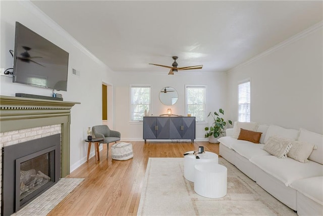 living room featuring a brick fireplace, crown molding, light hardwood / wood-style floors, and ceiling fan