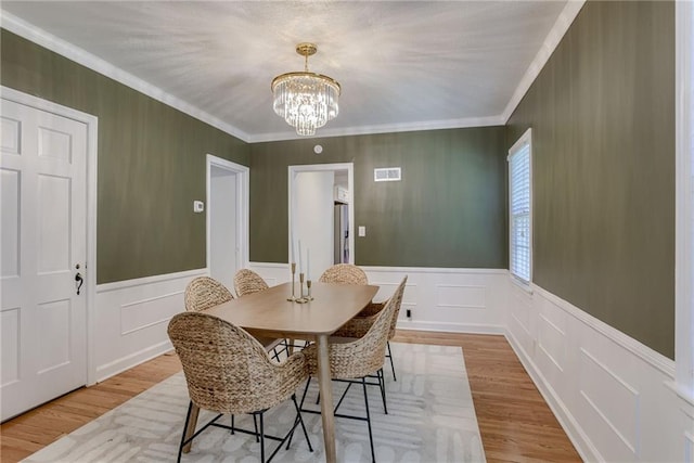 dining room featuring a notable chandelier, ornamental molding, and light hardwood / wood-style floors