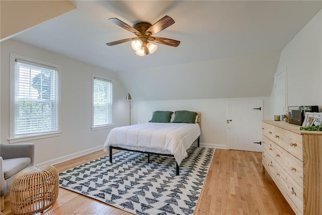 bedroom with ceiling fan, lofted ceiling, and light wood-type flooring