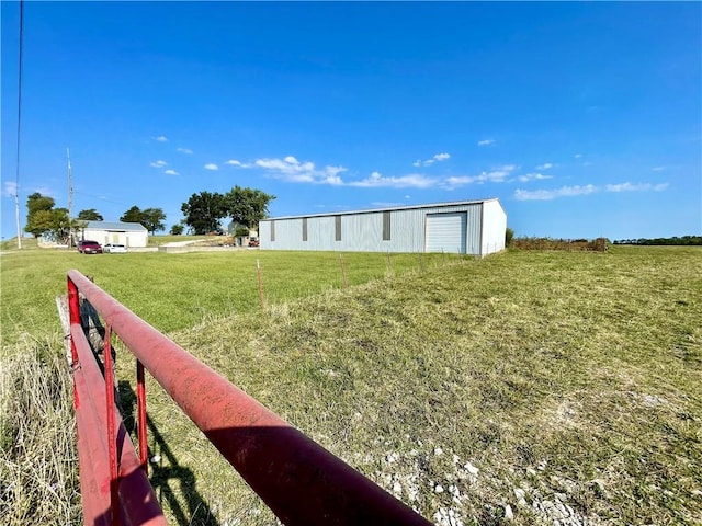 view of yard featuring an outbuilding, a rural view, and a garage