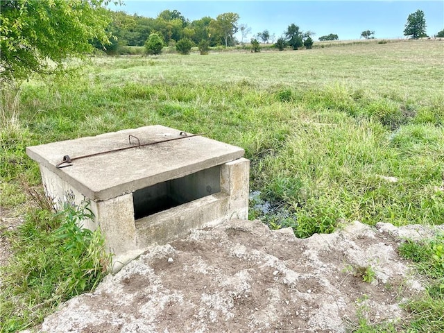 entry to storm shelter featuring a lawn and a rural view