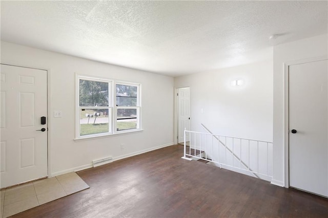 unfurnished room featuring dark hardwood / wood-style flooring and a textured ceiling