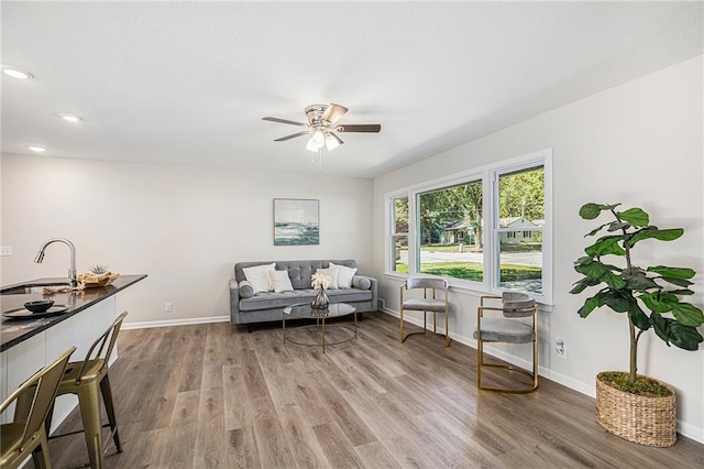 living room with hardwood / wood-style floors, sink, and ceiling fan