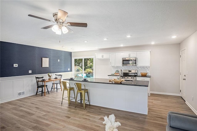 kitchen with light wood-type flooring, white cabinets, and appliances with stainless steel finishes