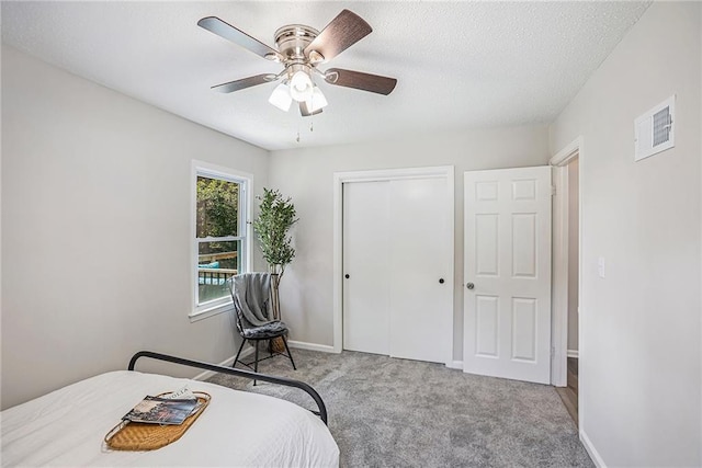 bedroom featuring a textured ceiling, a closet, ceiling fan, and light carpet