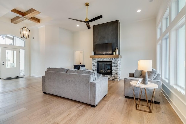 living room featuring plenty of natural light, a brick fireplace, light hardwood / wood-style floors, and beam ceiling