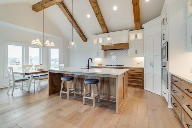 kitchen featuring white cabinets, sink, a kitchen island with sink, and decorative light fixtures