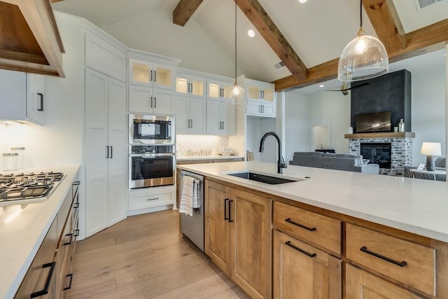 kitchen featuring white cabinetry, a fireplace, decorative light fixtures, sink, and appliances with stainless steel finishes