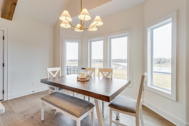 dining space featuring an inviting chandelier, a water view, light hardwood / wood-style flooring, and vaulted ceiling