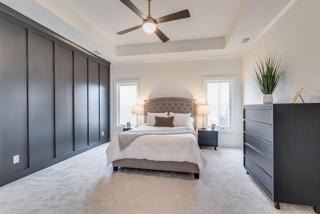 bedroom with ceiling fan, a tray ceiling, and light colored carpet