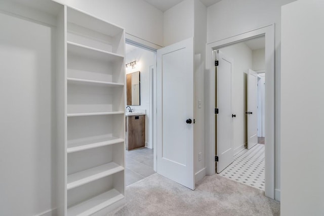 hallway featuring sink and light colored carpet