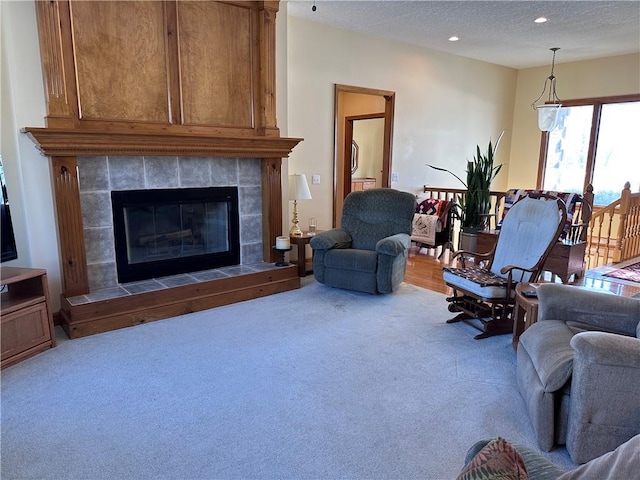 carpeted living room featuring a textured ceiling and a tiled fireplace