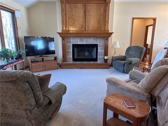 living room featuring lofted ceiling, a fireplace, and light colored carpet