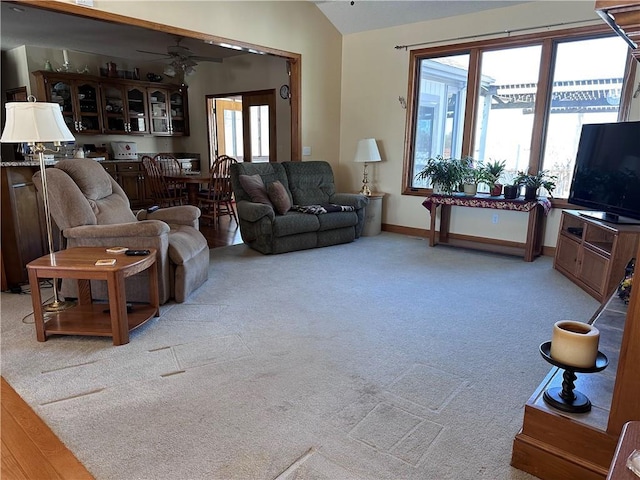 living room with lofted ceiling, ceiling fan, and light carpet