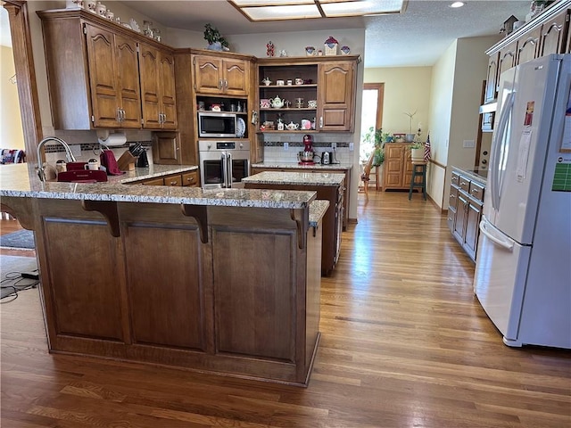 kitchen featuring white refrigerator, stainless steel oven, a kitchen bar, and dark hardwood / wood-style floors