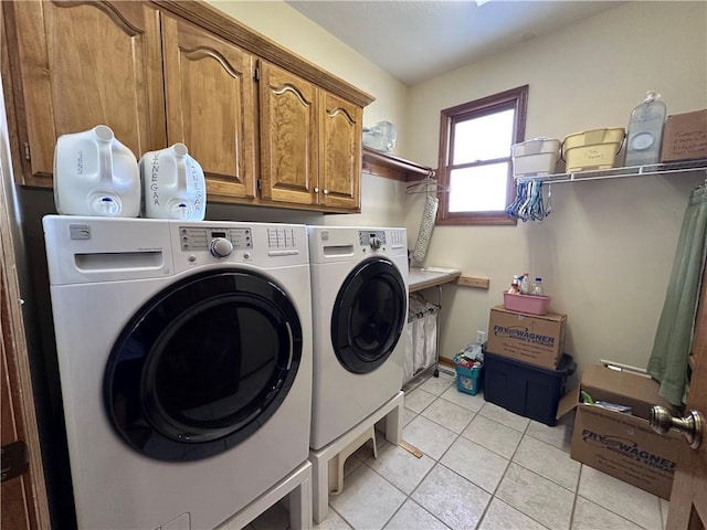 laundry room featuring light tile patterned floors, separate washer and dryer, and cabinets