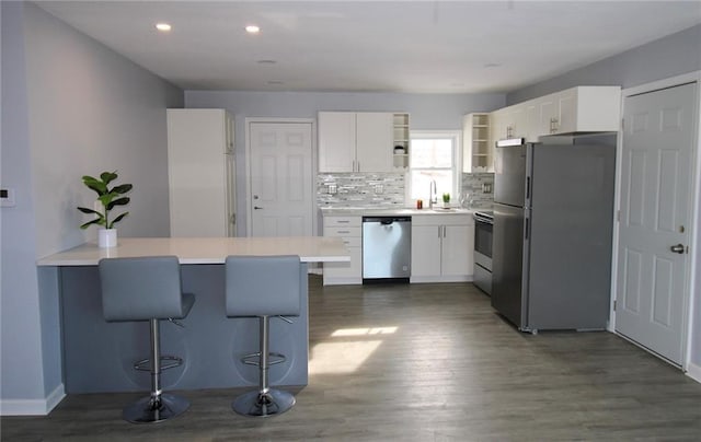 kitchen featuring kitchen peninsula, a kitchen bar, appliances with stainless steel finishes, and white cabinetry