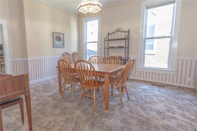 carpeted dining area with an inviting chandelier