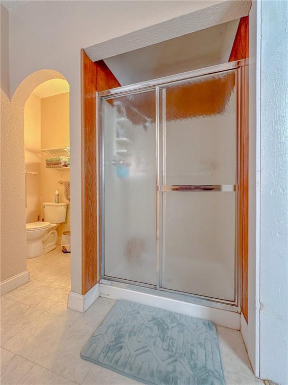 bathroom featuring a bidet, a shower with shower door, toilet, and tile patterned floors