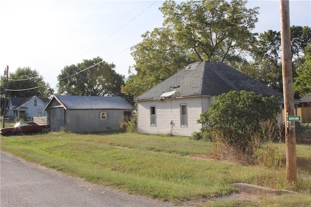 view of side of property with an outdoor structure and a yard