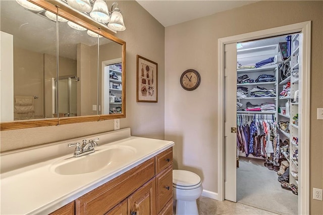 bathroom featuring vanity, toilet, walk in shower, and tile patterned flooring