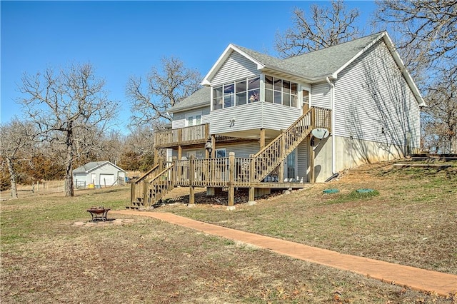 rear view of property with a wooden deck, a lawn, a fire pit, and a sunroom